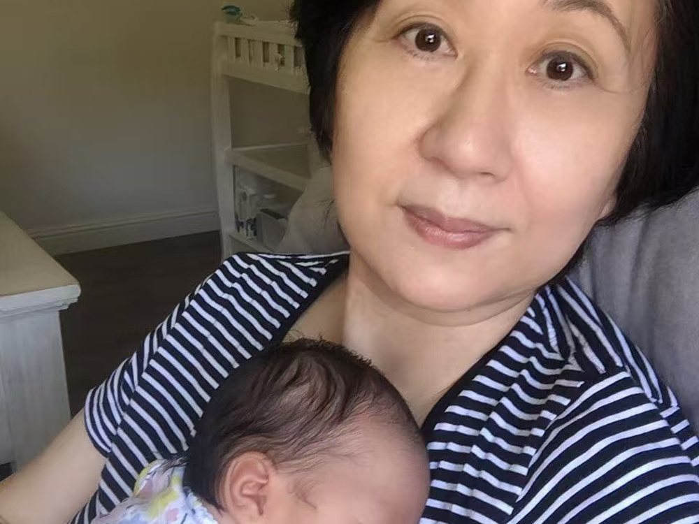 A newborn asleep against Cathie Li's chest