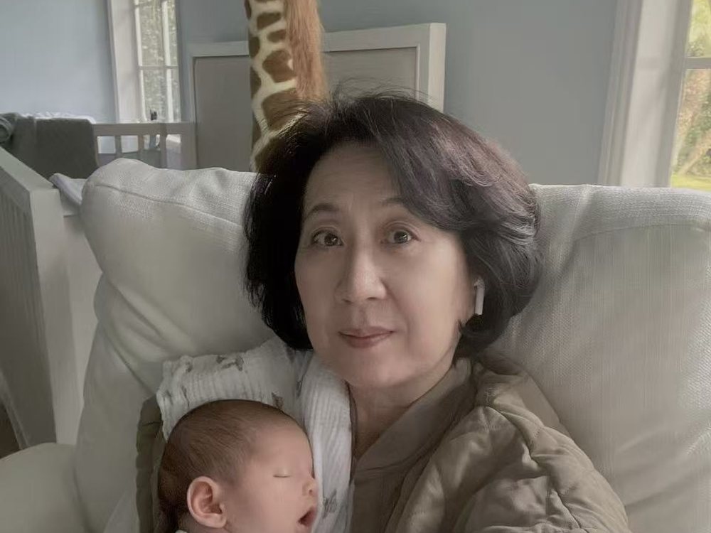 Cathie Li settling a swaddled newborn in a nursery