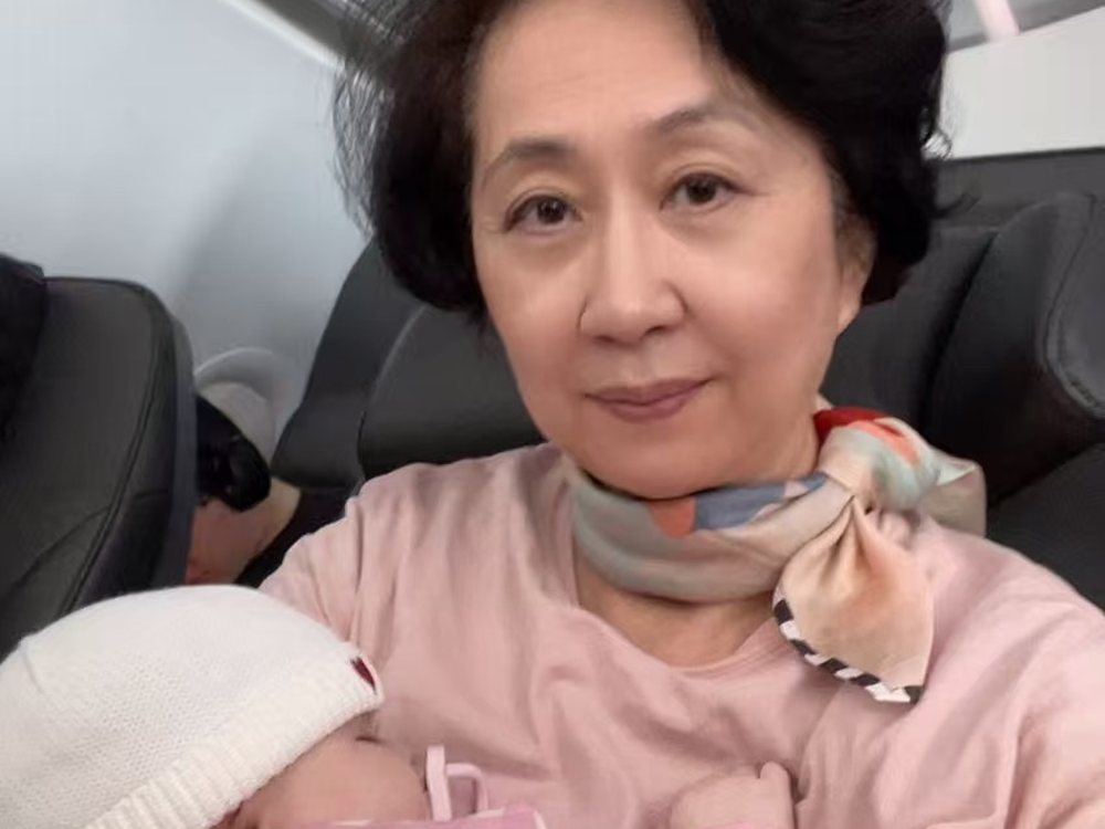 Cathie Li holding a sleeping infant on a flight while travelling with a family