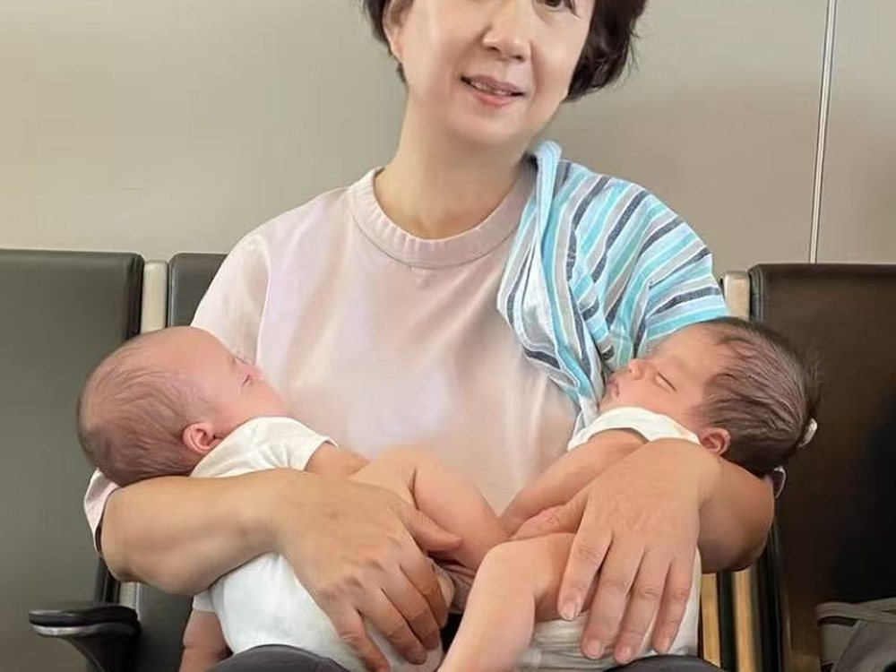 Cathie Li holding newborn twins, one in each arm
